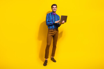 Poster - Full body photo of intelligent man wear stylish shirt vintage bow tie holding laptop typing message isolated on yellow color background