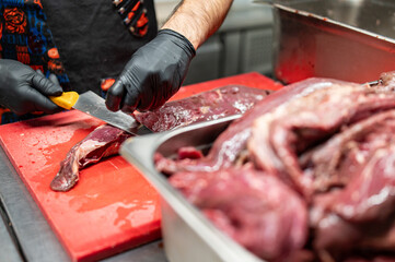 Wall Mural - Chef Butcher cutting beef meat with knife on kitchen