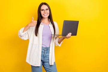 Canvas Print - Photo portrait of pretty young girl hold netbook showing thumb up wear trendy white outfit isolated on yellow color background