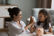 © fizkes - Indian mother and little daughter give high five sit at table with piggy bank. Caring mom teach child be thrifty, save pocket money for future education or purchases, thinking about tomorrow concept