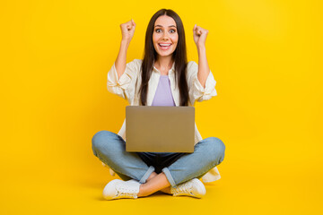 Sticker - Full size photo of delighted pretty girl sit floor use netbook raise fists triumph luck isolated on yellow color background