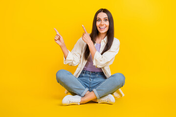 Poster - Full size portrait of pretty cheerful girl sit floor crossed legs indicate fingers empty space ad isolated on yellow color background