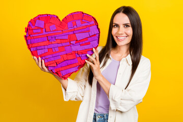 Sticker - Photo of toothy beaming adorable woman with long hairstyle dressed white jacket hold big paper heart isolated on yellow color background