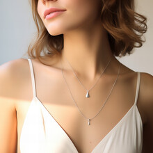 Blond Model Wearing A Silver Necklace With A Pendant And A White Summer Dress With Low Neckline