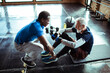© Davor - Smiling senior man working out with assistance of personal trainer at gym