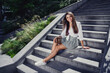 Photo of cute lovely cheerful girl sitting on stairs in park enjoying sunny warm weather outdoors