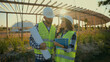 © Yuliia - Two Caucasian professional engineers constructor man holding scheme plan woman controller check tablet talk discuss analysing ecology project outside meadow countryside. Teamwork planning engineering