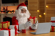 © New Africa - Santa Claus with Christmas gift using laptop at table in room