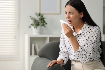 Poster - Suffering from allergy. Young woman with tissue sneezing at home, space for text