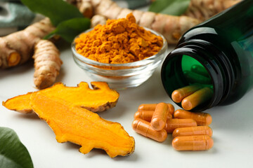 Turmeric roots, pills and powder on white table, closeup