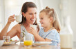 © K Davis/peopleimages.com - Mom, girl and breakfast in home with tea cup, comic laugh and relax with drink, food and bonding at table. Love, mother and daughter with coffee, juice and smile with care, happy and family house