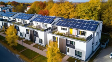 Wall Mural - Eco-friendly apartment buildings with solar panels on roofs surrounded by autumn trees. Apartment buildings with environmentally friendly large batteries on rooftops on edge of multi-colored trees