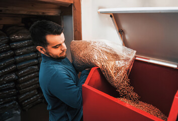 Man loading up pellet heating stove. Worker in a boiler room filling wooden pellet boiler. Biomass heating system. an alternative and sustainable way of generating heat and energy.