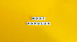 © photoopus - Most Popular Phrase on Alphabet Letter Blocks on Yellow Background. Minimal Aesthetic.
