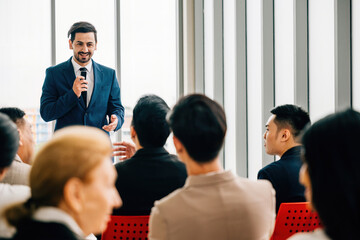 Wall Mural - In a meeting room, business leaders present reviews to a diverse group of colleagues who sit, listen, and participate. This showcases the spirit of teamwork and productive collaboration.