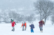© somemeans - Big family with children play snowballs outside during snowfall. Winter fun holidays. Games in winter outdoors.