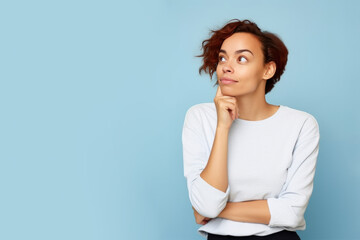 Wall Mural - Jeune femme en train de penser en regardant sur le côté vers le haut, espace libre pour du texte ou mise en scène, tenue claire fond uni bleu pâle