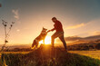 Border collie breed dog in the field giving his paw to his owner. Young man playing with his pet in the field at sunset