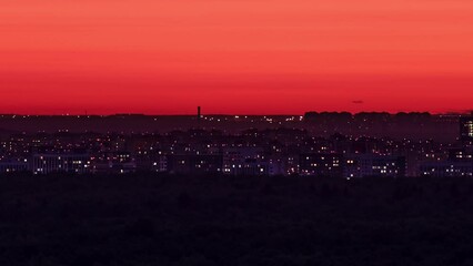 Wall Mural - Night city in the red light of the evening sun setting behind the horizon, time lapse.
