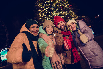 Poster - Photo of crowd four cheerful people have fun toothy smile demonstrate thumb up tree lights town center outdoors