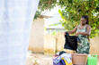 image of african lady holding cloths, basin and a laundry basket