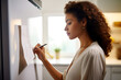 Young African American woman writing a grocery list on a sticky note on her refrigerator to avoid making unwise purchases