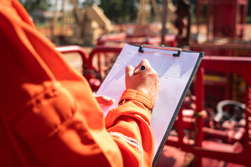 Wall Mural - Action of safety officer is writing and check on checklist document during safety audit and inspection at drilling site operation. Industrial expertise occupation working scene.