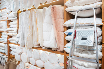 Poster - A lot of white bed linen on display in a store on wooden shelves
