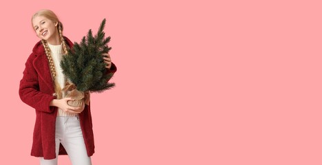 Wall Mural - Pretty young girl holding Christmas tree on pink background with space for text