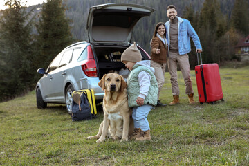 Canvas Print - Dog, cute little girl and her parents near car in mountains. Family traveling with pet