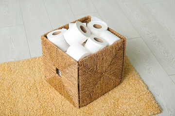 Wicker basket with toilet paper rolls on floor