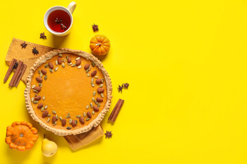 Wall Mural - Delicious pumpkin tart with almond and cup of hot tea on yellow background