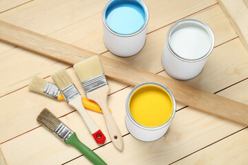 Wall Mural - Cans of colorful paints and brushes on wooden table, above view