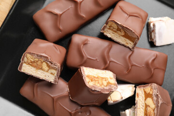 Wall Mural - Tasty chocolate bars with nougat and nuts on black plate, top view