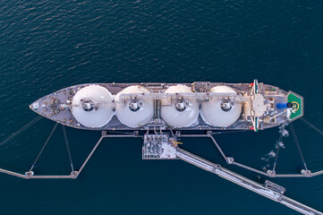 Aerial top down of Liquified Natural Gas LNG carrier moored to a small gas terminal. Fuel crisis. Sanctions