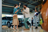 Fototapeta  - Cheerful couple dancing after buying new car in showroom.