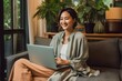 © riya - Happy young woman relaxing on a comfortable sofa while working on her laptop computer at home Generative AI