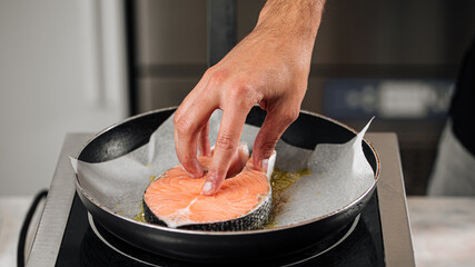 Wall Mural - Man cooking salmon steak roasting on parchment paper
