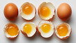 Whole and cracked open eggs with yolks on white surface.