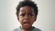 Close-up portrait of crying black boy toddler against white background with space for text, AI generated