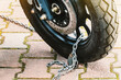 Motorcycle wheel tied with chain in parking, scooter wheel with disc brakes close-up