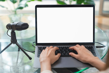 Woman hand type on the keyboard on laptop with mockup of blank screen and microphones for record podcast interview for radio.