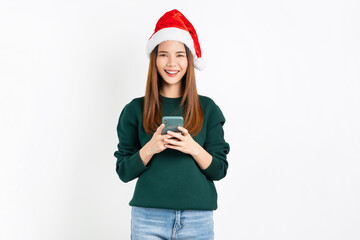 Cheerful beautiful Asian woman wearing red Christmas hat with holding smartphone and smiling on white background.