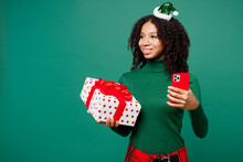 Merry Little Kid Teen Girl Wear Hat Casual Clothes Posing Use Mobile Cell Phone Hold Present Box With Gift Bow Look Aside Isolated On Plain Green Background. Happy New Year Christmas Holiday Concept.