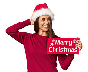 Wall Mural - Middle-aged woman with Merry Christmas sign in studio touching back of head, thinking and making a choice.