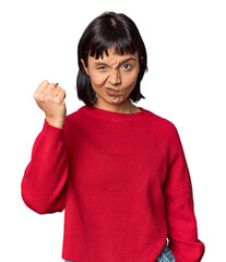 Wall Mural - Young Hispanic woman with short black hair in studio showing fist to camera, aggressive facial expression.