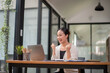 © Wasana - Happy business woman celebrating victory while receiving good news on her laptop, excited about success.