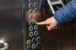 A man presses the floor button in the elevator of the business center