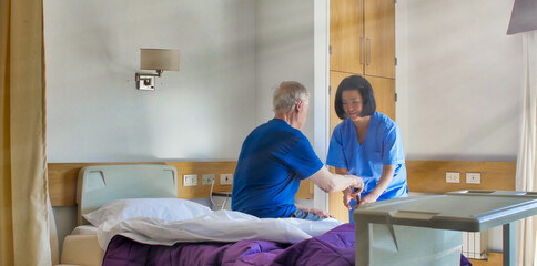 Sticker - Asian female doctor helping elderly patient in hospital bed. Rehabilitation and retirement concept