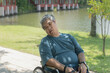 Middle-aged Asian man sitting in a wheelchair The mouth is distorted due to nervous system illness and paralysis. according to the concept of health care